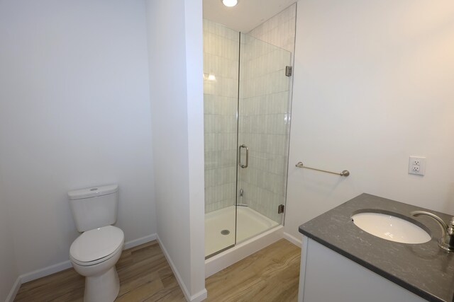 bathroom featuring hardwood / wood-style floors, vanity, toilet, and a shower with door