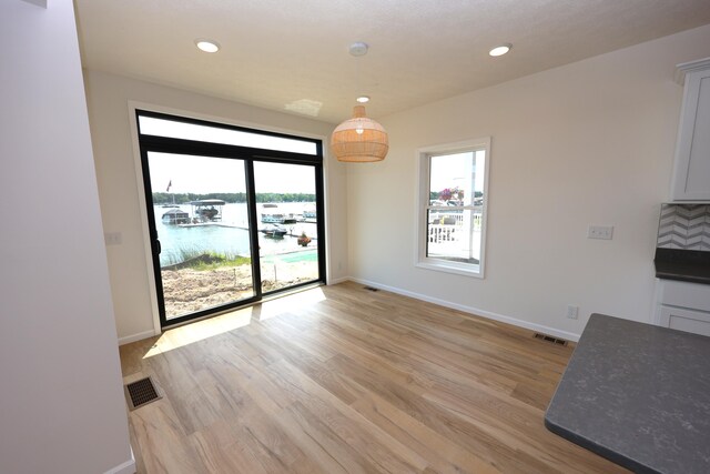 unfurnished dining area with a water view and light hardwood / wood-style floors