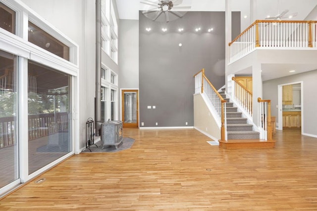 unfurnished living room featuring a towering ceiling, ceiling fan, and light hardwood / wood-style flooring