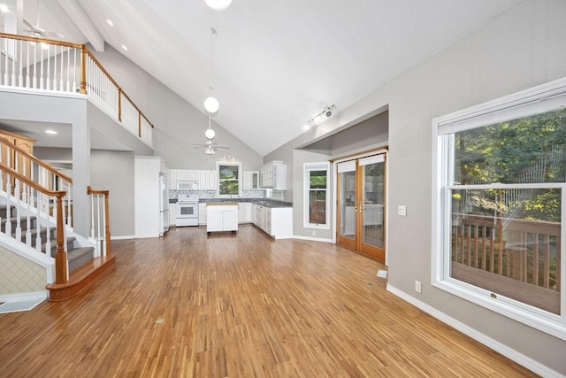 unfurnished living room featuring hardwood / wood-style flooring, ceiling fan, and high vaulted ceiling