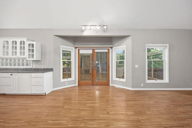 unfurnished dining area featuring light wood-type flooring and french doors