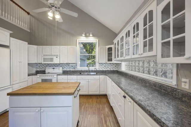 kitchen featuring white appliances, sink, a center island, white cabinetry, and butcher block countertops