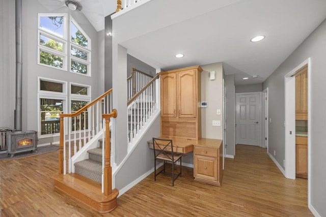 stairway with a wood stove, a wealth of natural light, and hardwood / wood-style flooring