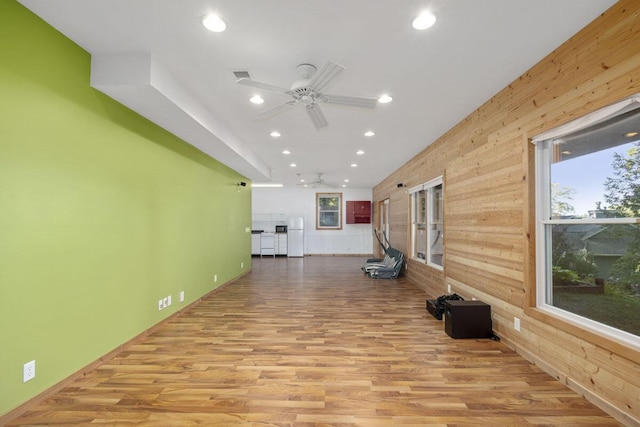 exercise room with light hardwood / wood-style flooring, ceiling fan, and wood walls