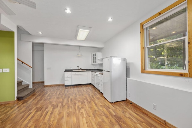 kitchen featuring light hardwood / wood-style flooring, hanging light fixtures, white refrigerator, sink, and white cabinetry