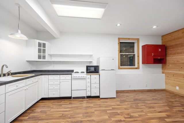 kitchen featuring white appliances, sink, light wood-type flooring, pendant lighting, and wood walls