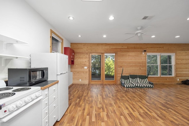 kitchen featuring light hardwood / wood-style flooring, white electric range, and wooden walls