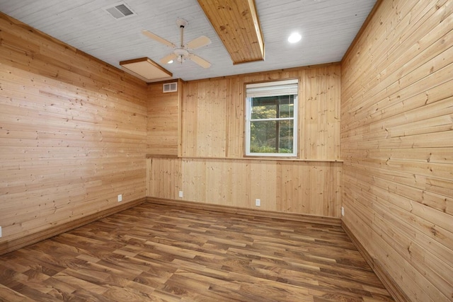 empty room featuring hardwood / wood-style flooring, ceiling fan, and wood walls