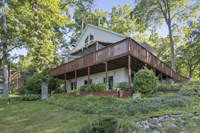 back of property featuring a deck and a lawn