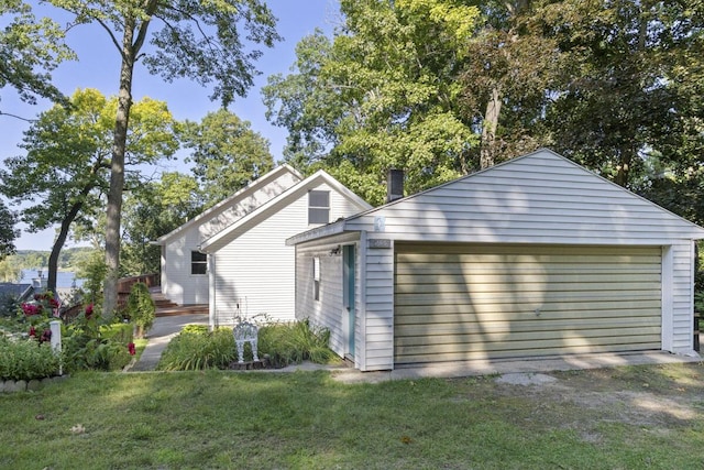 exterior space featuring a garage, a lawn, and an outbuilding