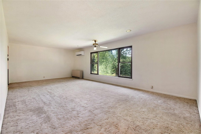 empty room with carpet, a ceiling fan, baseboards, a wall mounted AC, and a textured ceiling