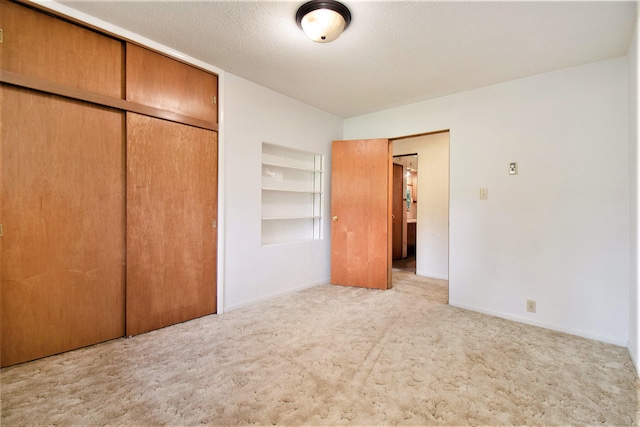 unfurnished bedroom featuring light carpet, a closet, and a textured ceiling