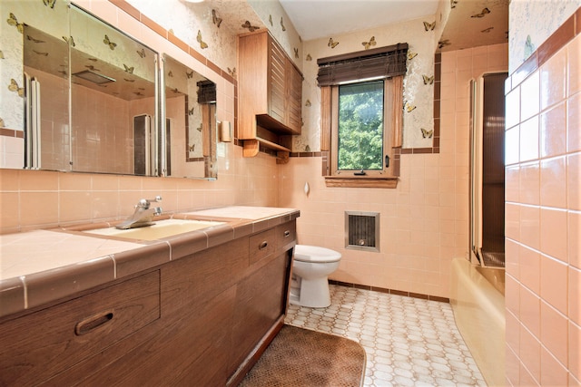 bathroom with decorative backsplash, tile patterned floors, vanity, tile walls, and toilet