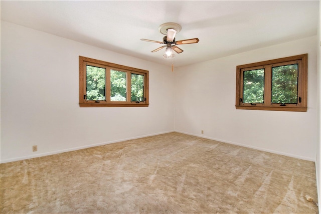 carpeted empty room with baseboards and a ceiling fan