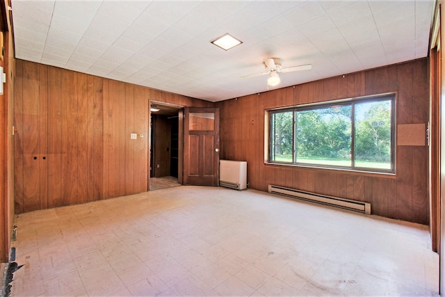 tiled empty room featuring ceiling fan, wooden walls, and baseboard heating