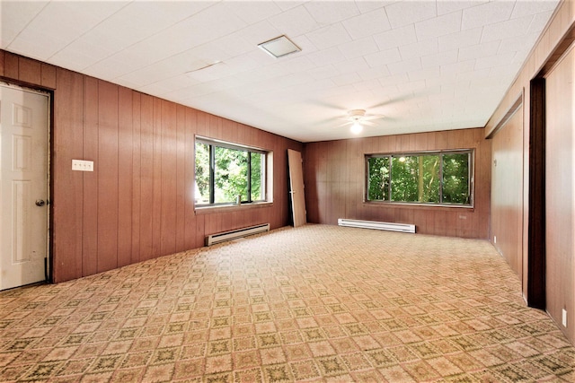 spare room with a baseboard heating unit, wooden walls, and a ceiling fan