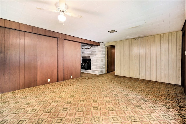 interior space featuring wooden walls, a fireplace, and ceiling fan