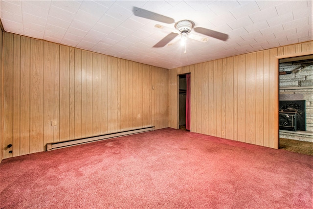 spare room featuring a fireplace, wooden walls, a baseboard radiator, and carpet flooring