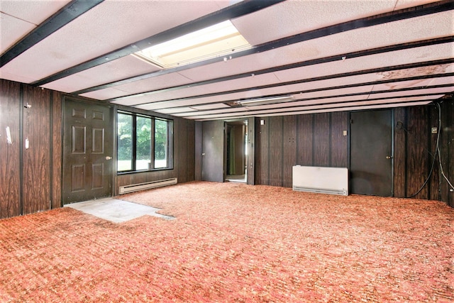 misc room featuring baseboard heating, carpet flooring, and wooden walls