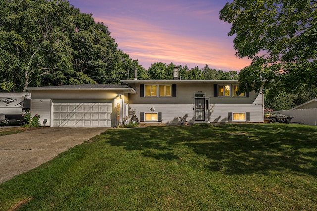 bi-level home featuring a garage and a lawn