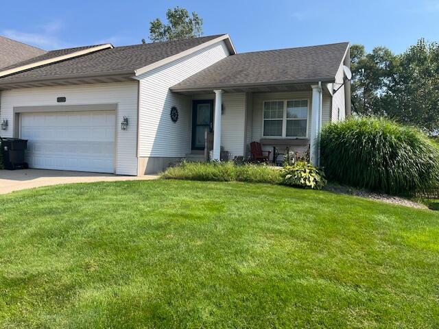 ranch-style home with concrete driveway, a front lawn, a garage, and a shingled roof