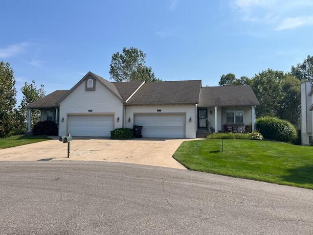 ranch-style house with a garage, driveway, and a front lawn