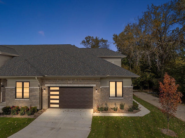 view of front of house with an attached garage, brick siding, driveway, and a shingled roof