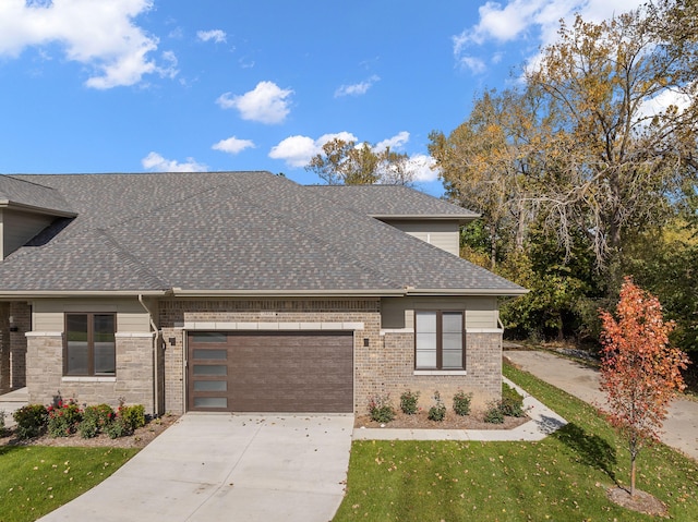 view of front of house with a front yard, roof with shingles, concrete driveway, a garage, and brick siding