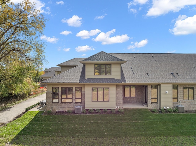 view of front facade featuring brick siding, a front lawn, and roof with shingles