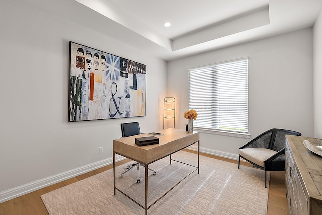 office area featuring recessed lighting, a raised ceiling, light wood-type flooring, and baseboards