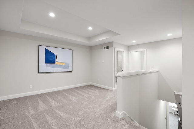 carpeted empty room with a raised ceiling, recessed lighting, baseboards, and visible vents