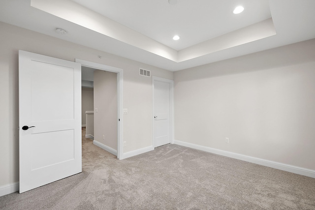 unfurnished bedroom with visible vents, baseboards, carpet floors, recessed lighting, and a raised ceiling