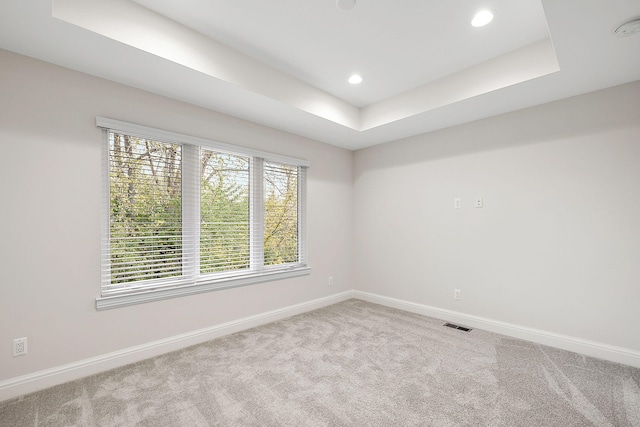 spare room featuring a raised ceiling, recessed lighting, baseboards, and carpet floors