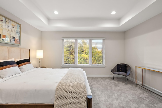 carpeted bedroom featuring recessed lighting, a raised ceiling, and baseboards