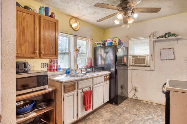 kitchen featuring ceiling fan, black fridge, sink, a textured ceiling, and stove