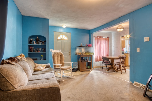 carpeted living room featuring a textured ceiling and built in shelves