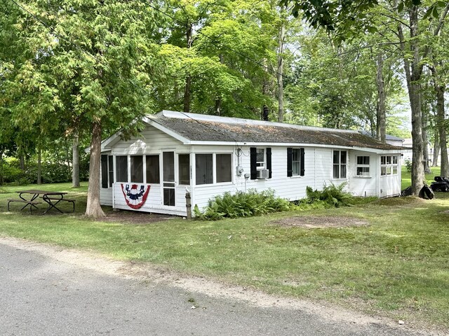 single story home featuring a sunroom, cooling unit, and a front lawn