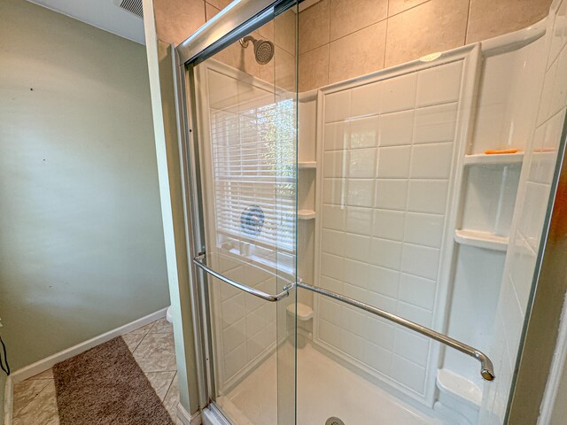 bathroom with an enclosed shower and tile patterned floors