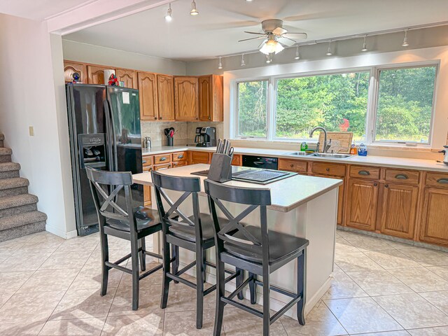 kitchen featuring fridge with ice dispenser, a kitchen bar, sink, plenty of natural light, and ceiling fan