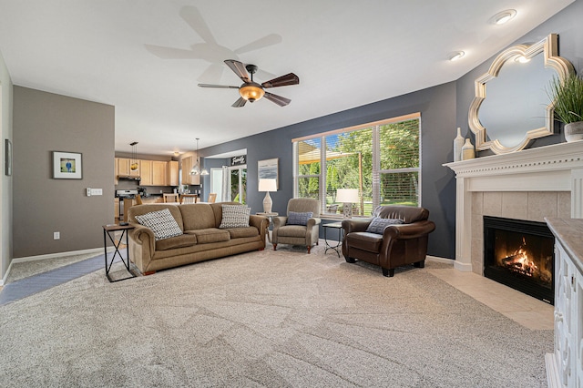 living room featuring a fireplace, ceiling fan, and light colored carpet