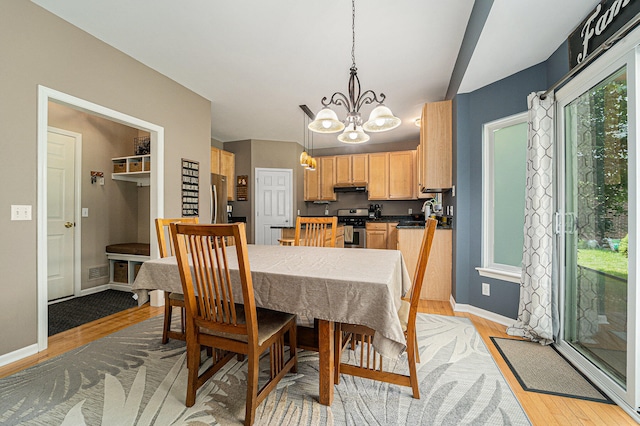 dining space with light wood-type flooring and a notable chandelier