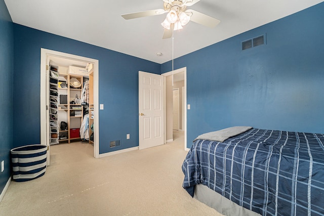 bedroom featuring a walk in closet, a closet, carpet, and ceiling fan