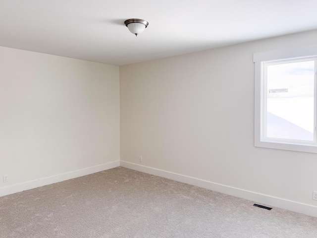 spare room with light colored carpet, plenty of natural light, visible vents, and baseboards