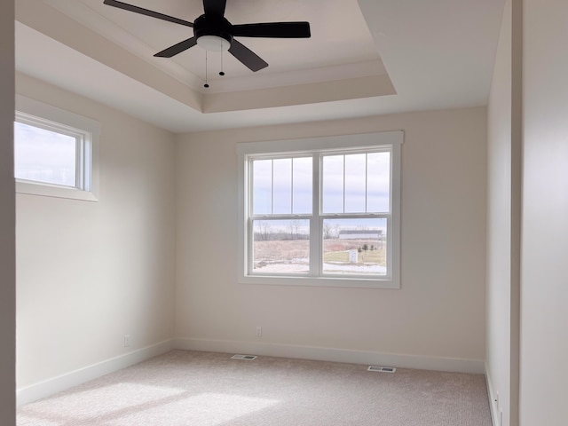 carpeted empty room featuring baseboards, visible vents, and a raised ceiling