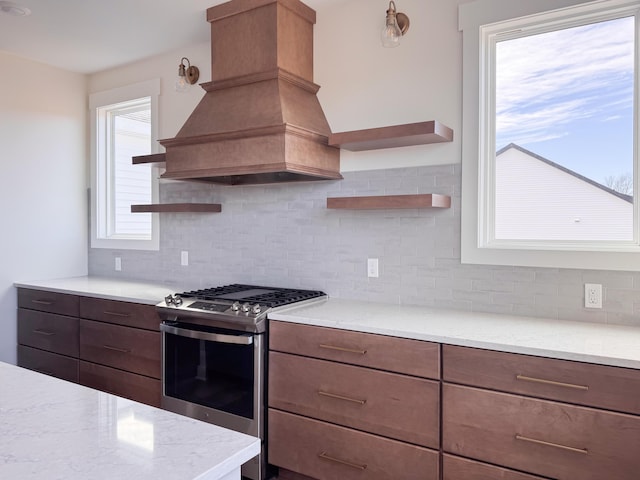 kitchen with decorative backsplash, stainless steel range with gas cooktop, custom exhaust hood, and open shelves