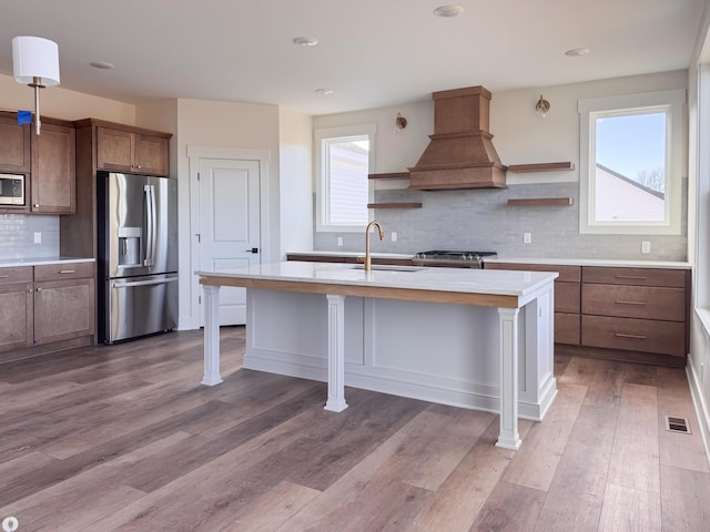 kitchen with stainless steel appliances, premium range hood, a sink, visible vents, and open shelves