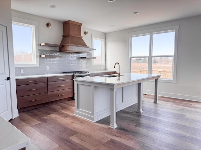 kitchen featuring light countertops, gas stove, custom range hood, and a sink