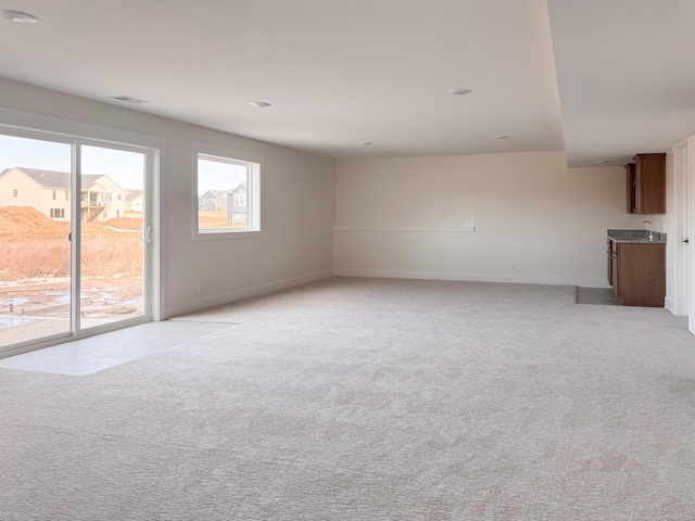 unfurnished living room with light colored carpet and baseboards