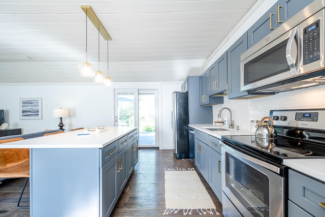 kitchen with dark wood-type flooring, a kitchen bar, appliances with stainless steel finishes, sink, and a center island