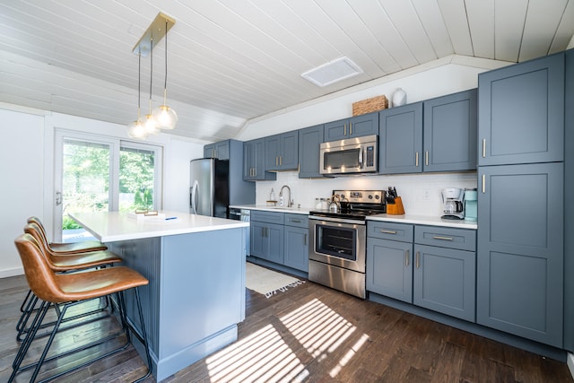 kitchen with stainless steel appliances, decorative backsplash, dark hardwood / wood-style floors, a kitchen island, and a breakfast bar